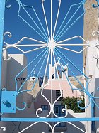 A picture of a metal gate shaped like the sun's rays in Oia